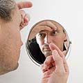 Einsetzen der Kontaktlinse vor dem Spiegel